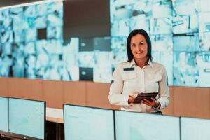 retrato de hembra seguridad operador mientras trabajando en un datos sistema controlar habitación oficinas técnico operador trabajando a puesto de trabajo con múltiple pantallas, seguridad Guardia trabajando en múltiple monitores foto