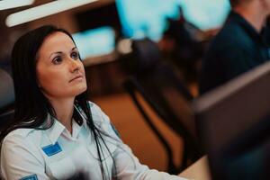 Female security operator working in a data system control room offices Technical Operator Working at workstation with multiple displays, security guard working on multiple monitors photo