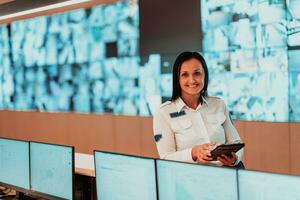 retrato de hembra seguridad operador mientras trabajando en un datos sistema controlar habitación oficinas técnico operador trabajando a puesto de trabajo con múltiple pantallas, seguridad Guardia trabajando en múltiple monitores foto