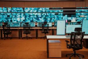 Empty interior of big modern security system control room, workstation with multiple displays, monitoring room with at security data center Empty office, desk, and chairs at a main CCTV security data photo