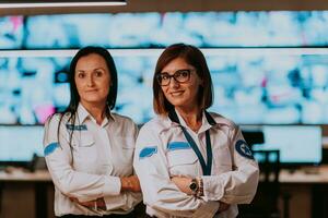 group portrait of female security operator while working in a data system control room offices Technical Operator Working at workstation with multiple displays, security guard working on multiple mon photo