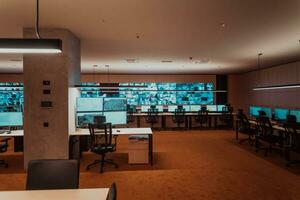 Empty interior of big modern security system control room, workstation with multiple displays, monitoring room with at security data center Empty office, desk, and chairs at a main CCTV security data photo