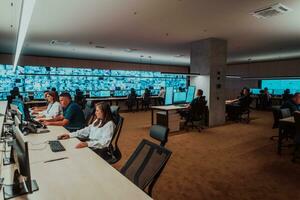 Group of Security data center operators working in a CCTV monitoring room looking on multiple monitors Officers Monitoring Multiple Screens for Suspicious Activities Team working on the System Contr photo