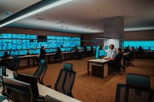 Group of Security data center operators working in a CCTV monitoring room looking on multiple monitors Officers Monitoring Multiple Screens for Suspicious Activities Team working on the System Contr photo