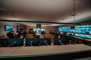 Group of Security data center operators working in a CCTV monitoring room looking on multiple monitors Officers Monitoring Multiple Screens for Suspicious Activities Team working on the System Contr photo