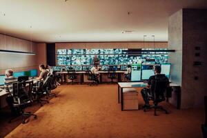 Group of Security data center operators working in a CCTV monitoring room looking on multiple monitors Officers Monitoring Multiple Screens for Suspicious Activities Team working on the System Contr photo