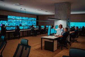 Group of Security data center operators working in a CCTV monitoring room looking on multiple monitors Officers Monitoring Multiple Screens for Suspicious Activities Team working on the System Contr photo