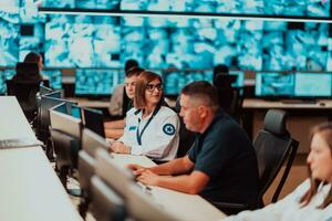 Group of Security data center operators working in a CCTV monitoring room looking on multiple monitors Officers Monitoring Multiple Screens for Suspicious Activities Team working on the System Contr photo