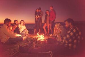 Couple enjoying with friends at sunset on the beach photo