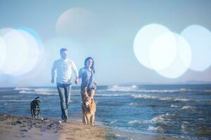 pareja con perro divirtiéndose en la playa el día del otoño foto