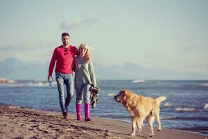 pareja con perro divirtiéndose en la playa el día del otoño foto