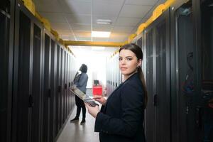 Female engineer working on a tablet computer in server room photo