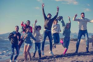 young friends jumping together at autumn beach photo