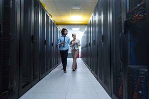 engineer showing working data center server room to female chief photo