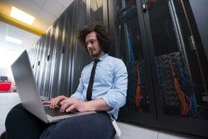 engineer working on a laptop in server room photo