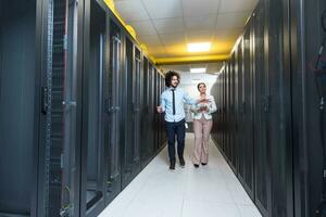 engineer showing working data center server room to female chief photo