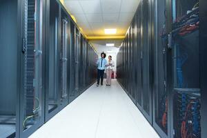 engineer showing working data center server room to female chief photo