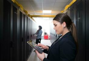 Female engineer working on a tablet computer in server room photo