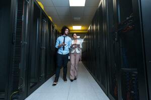 engineer showing working data center server room to female chief photo