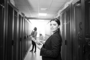 Female engineer working on a tablet computer in server room photo