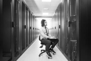 engineer working on a laptop in server room photo