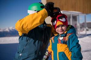 father preparing his little son for the first time on a snowboard photo