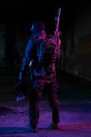 Army soldier in Combat Uniforms with an assault rifle and combat helmet night mission dark background. Blue and purple gel light effect. photo