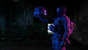 Army soldier in Combat Uniforms with an assault rifle and combat helmet night mission dark background. Blue and purple gel light effect. photo