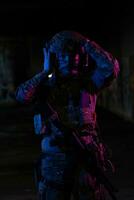 Army soldier in Combat Uniforms with an assault rifle and combat helmet night mission dark background. Blue and purple gel light effect. photo