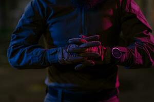 Photo of a fully equipped soldier in black armor tactical vest and gloves standing on black background closeup front view.