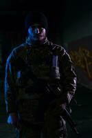 Army soldier in Combat Uniforms with an assault rifle and combat helmet night mission dark background. Blue and purple gel light effect. photo