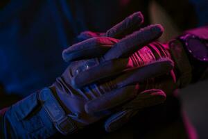 Photo of a fully equipped soldier in black armor tactical vest and gloves standing on black background closeup front view.