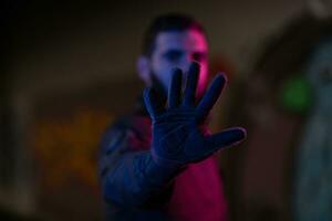 Photo of a fully equipped soldier in black armor tactical vest and gloves standing on black background closeup front view.