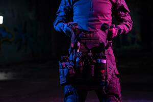 Ejército soldado en combate uniformes con un asalto rifle y combate casco noche misión oscuro antecedentes. azul y púrpura gel ligero efecto. foto