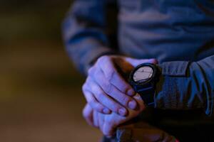 Modern warfare soldier checking navigation, time and other information on a smartwatch. Dark night black background. photo