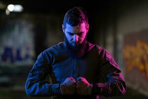 Photo of a fully equipped soldier in black armor tactical vest and gloves standing on black background closeup front view.