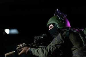 Ejército soldado en combate uniformes con un asalto rifle y combate casco noche misión oscuro antecedentes. azul y púrpura gel ligero efecto. foto