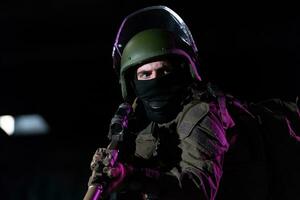 Ejército soldado en combate uniformes con un asalto rifle y combate casco noche misión oscuro antecedentes. azul y púrpura gel ligero efecto. foto