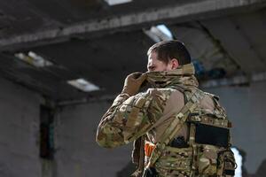 Army soldier in Combat Uniforms with an assault rifle and face protection mask. photo