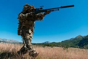 army soldier holding sniper rifle with scope and aiming in forest. war, army, technology and people concept photo