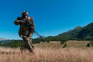 army soldier holding sniper rifle with scope and aiming in forest. war, army, technology and people concept photo