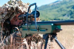 army soldier holding sniper rifle with scope and aiming in forest. war, army, technology and people concept photo