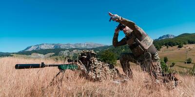 Sniper soldier assisted by an assistant to observe the area to be targeted with modern warfare tactical virtual reality goggles aerial drone military technology. photo