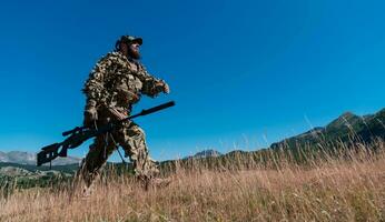 army soldier holding a sniper rifle with scope and walking in the forest. war, army, technology and people concept. photo