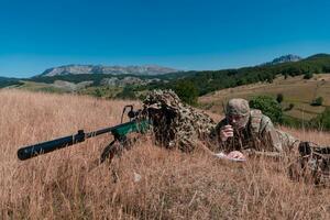 Sniper soldier assisted by an assistant to observe the area to be targeted with modern warfare tactical virtual reality goggles aerial drone military technology. photo