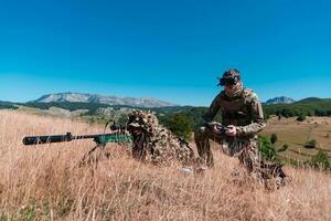 Sniper soldier assisted by an assistant to observe the area to be targeted with modern warfare tactical virtual reality goggles aerial drone military technology. photo