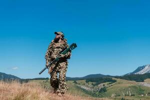 Ejército soldado participación un francotirador rifle con alcance y caminando en el bosque. guerra, ejército, tecnología y personas concepto. foto