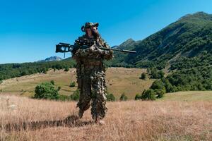 Ejército soldado participación un francotirador rifle con alcance y caminando en el bosque. guerra, ejército, tecnología y personas concepto. foto