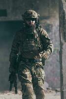 un soldado barbudo con uniforme de las fuerzas especiales camina por un edificio abandonado después de una misión exitosa. enfoque de selección foto