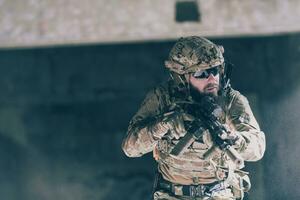 A bearded soldier in uniform of special forces in a dangerous military action in a dangerous enemy area. Selective focus photo